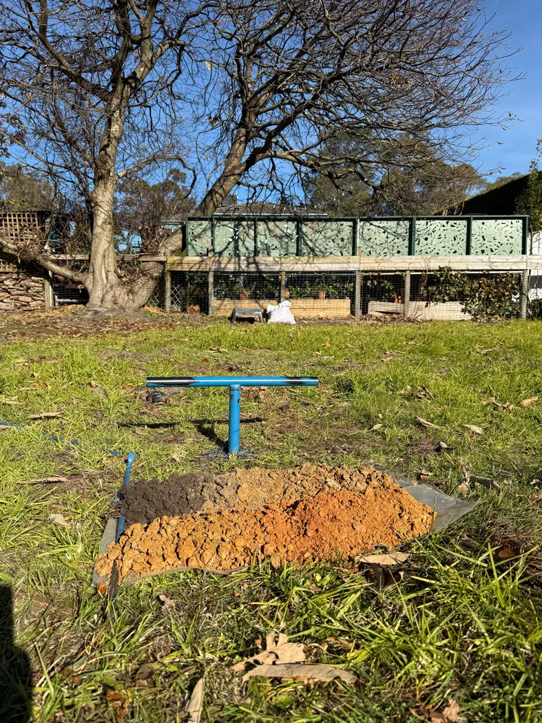 Hand auger and excavated soil laid out on a sheet at a residential site