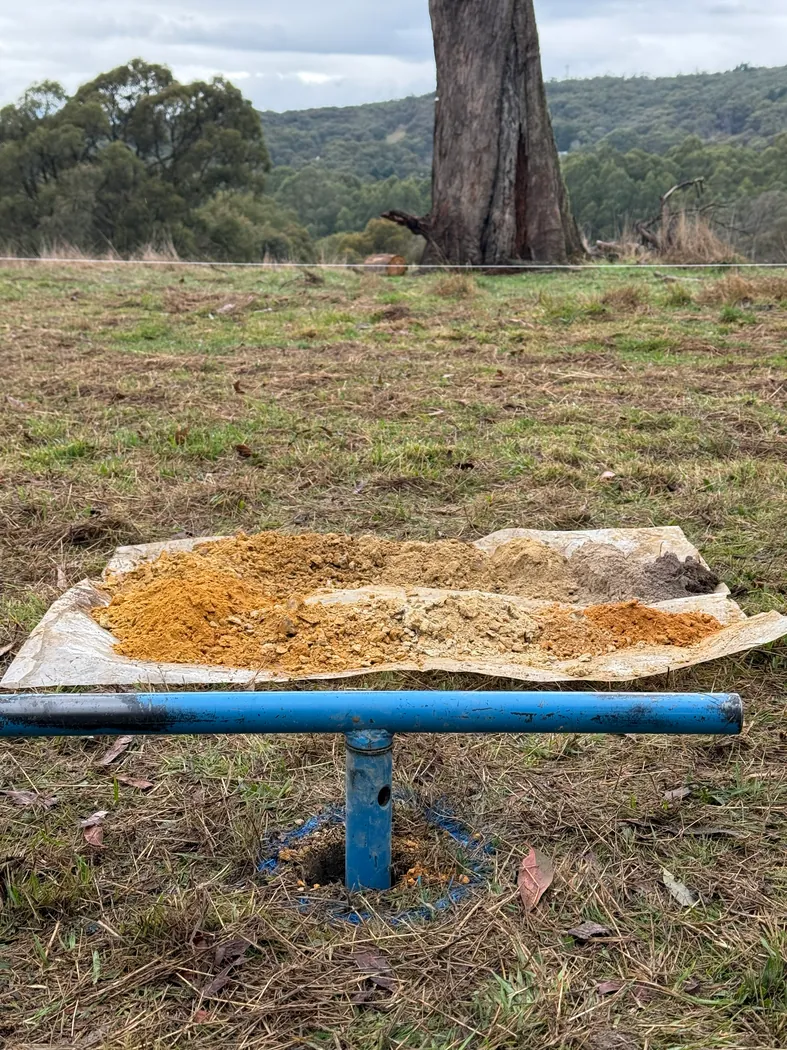 Hand auger and soil samples on an open site with trees in the background