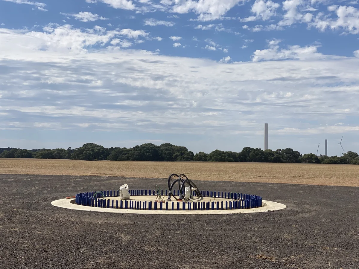 Wind turbine foundation in the foreground, with turbine towers and open countryside beyond.