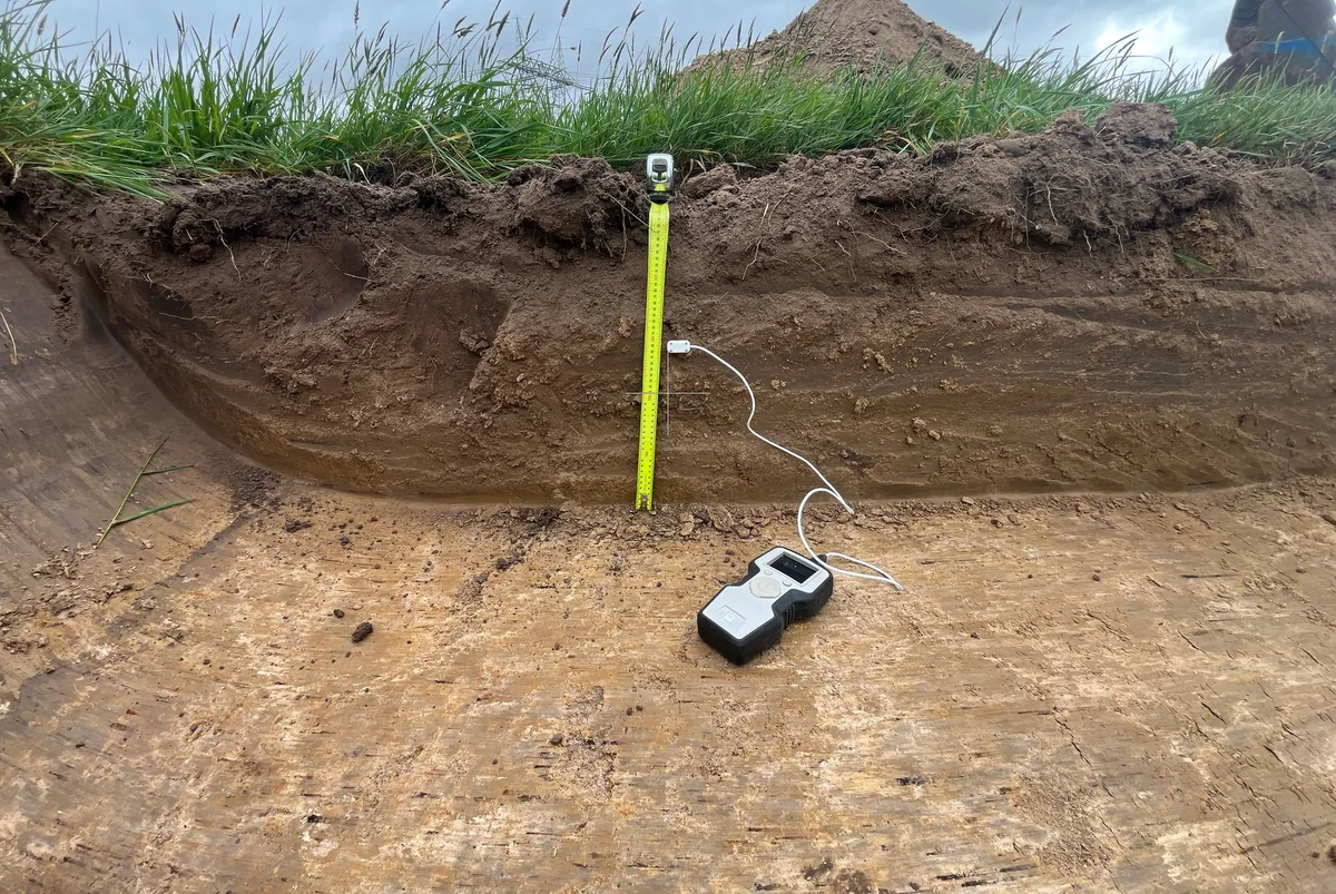 Thermal testing equipment and probe positioned against exposed soil.
