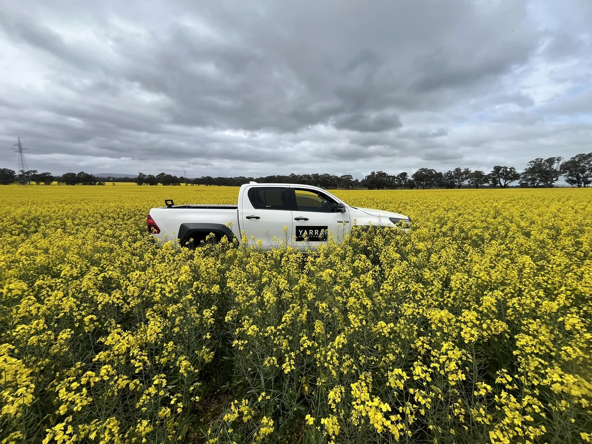 Yarra Geotechnics field vehicle beside a flowering crop.